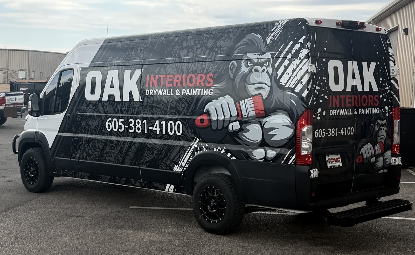 Oak Interiors van with black, white and red gorilla-themed graphics across the cargo side and rear doors, beside a plain white front cab