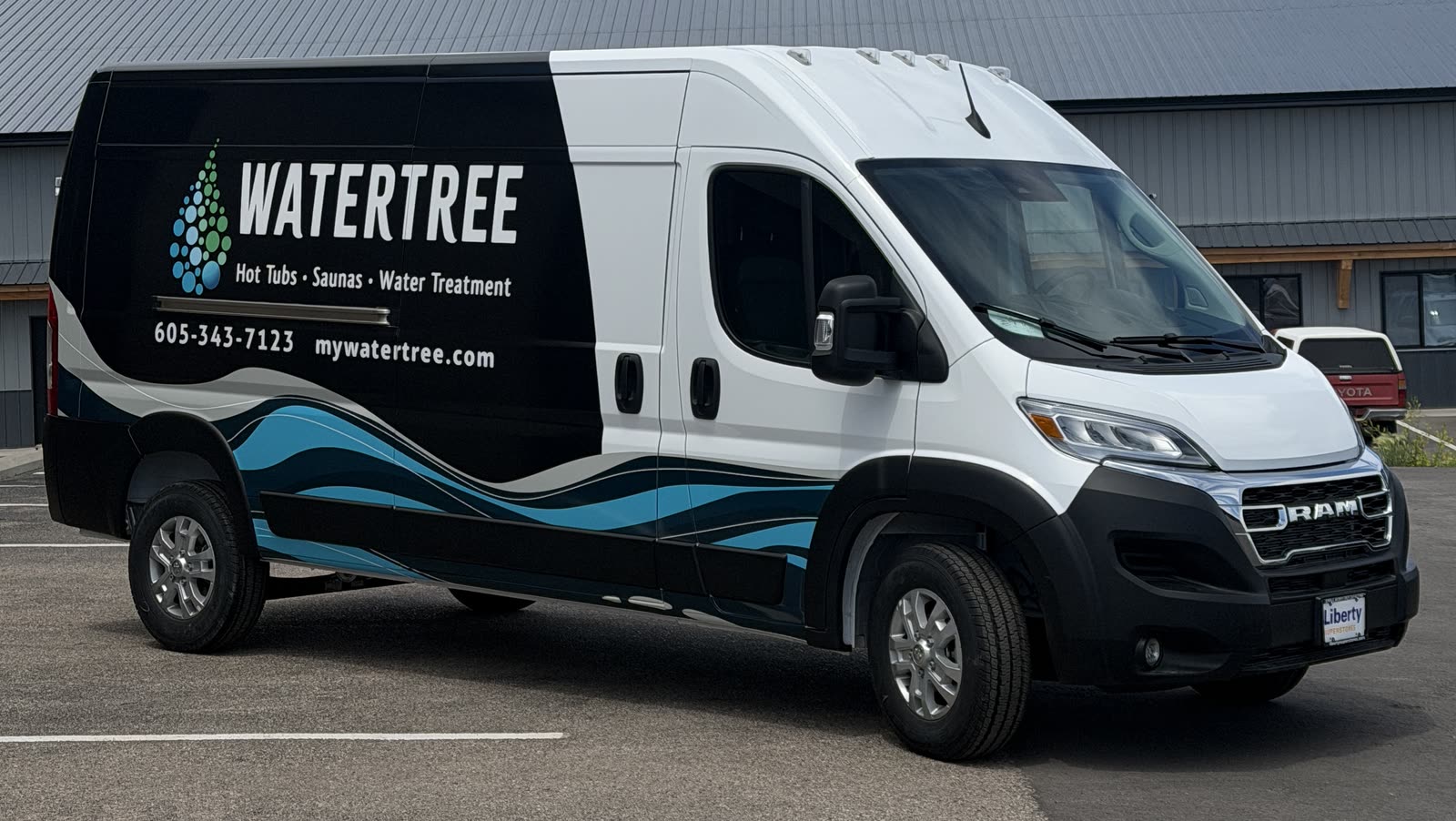 Watertree service van with black cargo-side branding and turquoise lower-body waves alongside a plain white upper cab and front